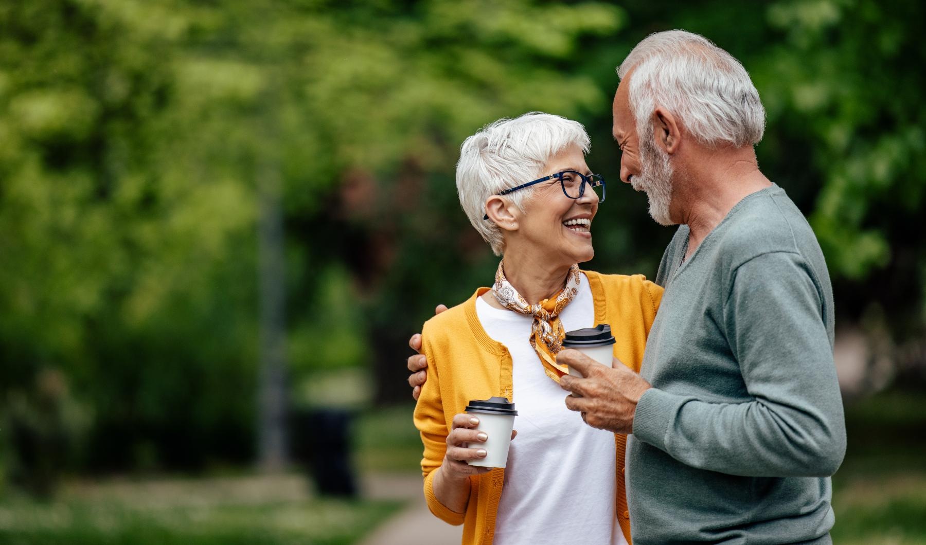Close to the center of everything a man and woman holding coffee cups in the park