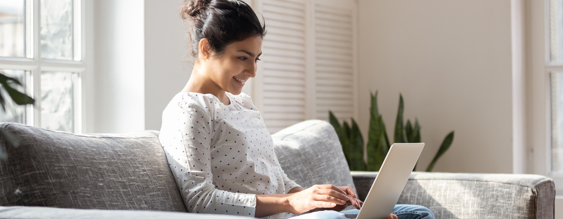 a woman sitting on a couch using a laptop